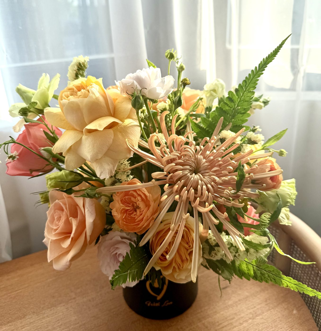 Peach and cream rose arrangement in a black vase